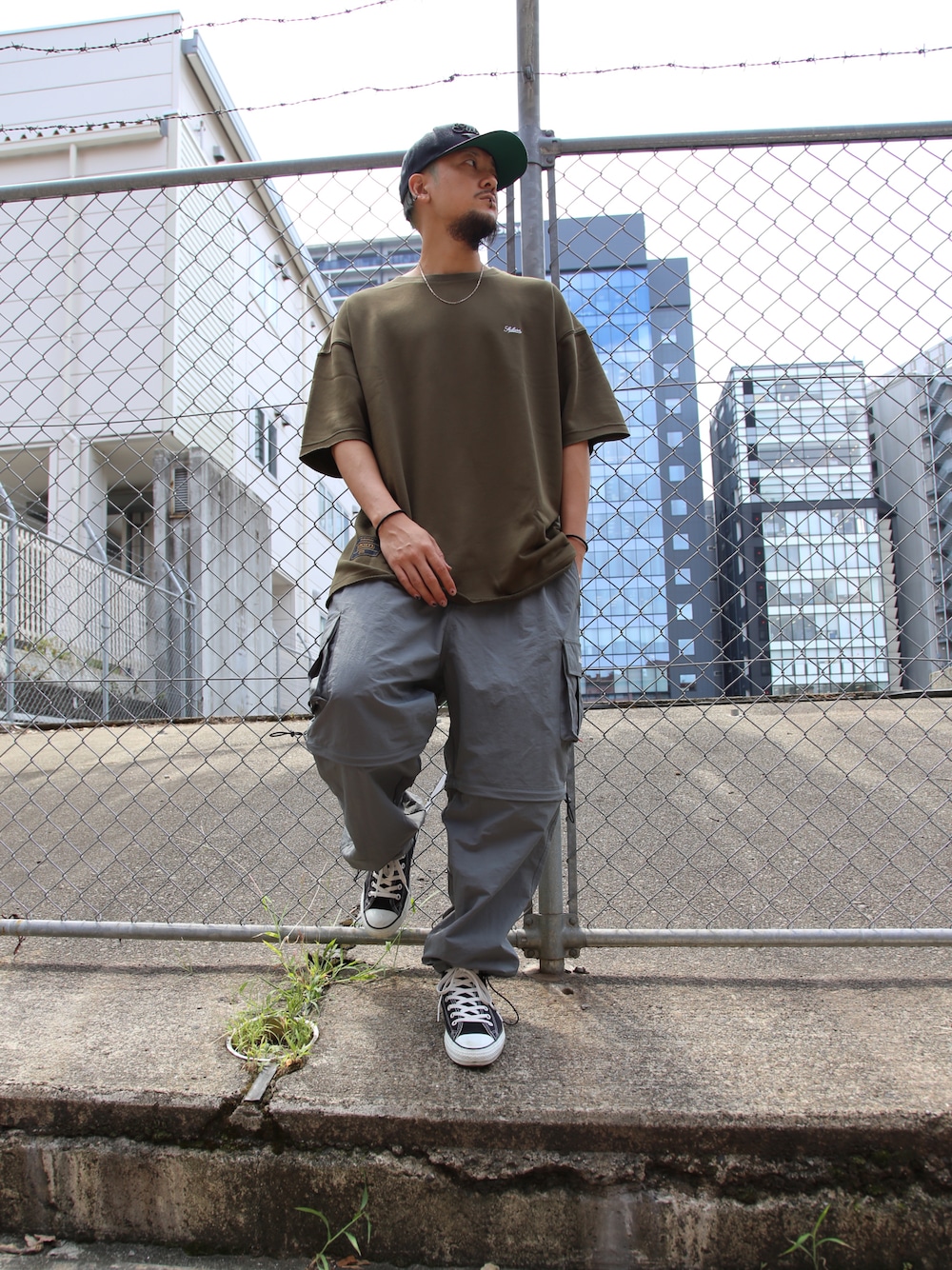 グレー系のカーゴパンツ、グリーン系のTシャツ/カットソー、シルバー系のネックレスを着用したメンズの夏コーディネートの1枚目の写真