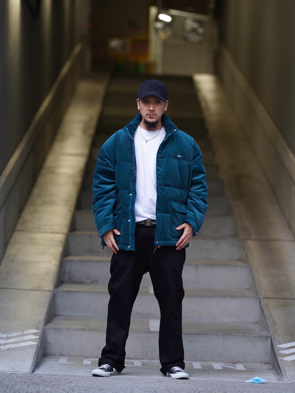 ブラック系のチノパンツ、ブルー系のダウンジャケット/コート、ブラック系のキャップを着用したメンズの秋コーディネートの1枚目の写真