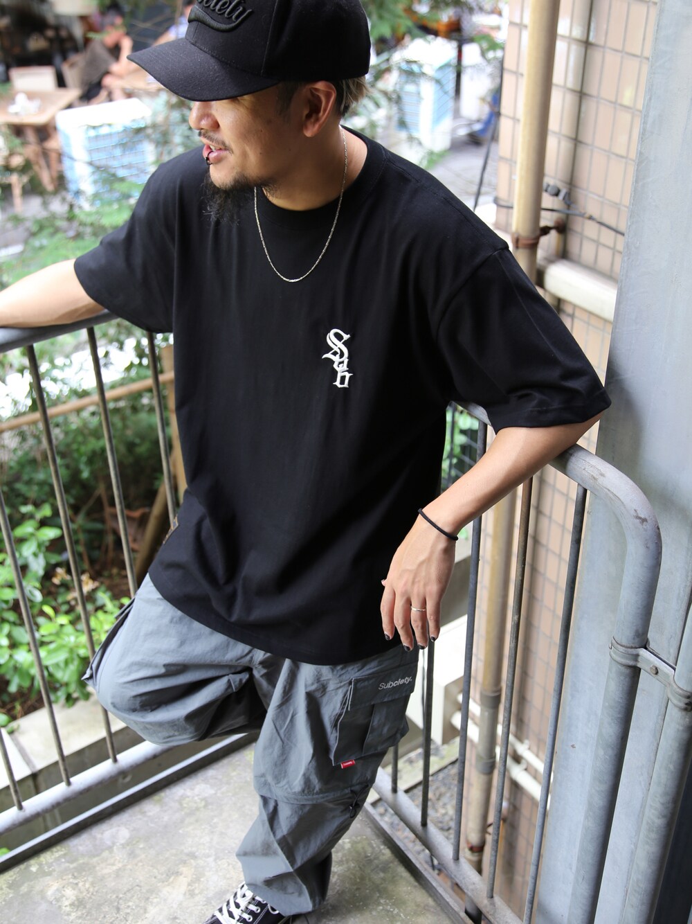 グレー系のカーゴパンツ、ブラック系のTシャツ/カットソー、シルバー系のネックレスを着用したメンズの夏コーディネートの1枚目の写真