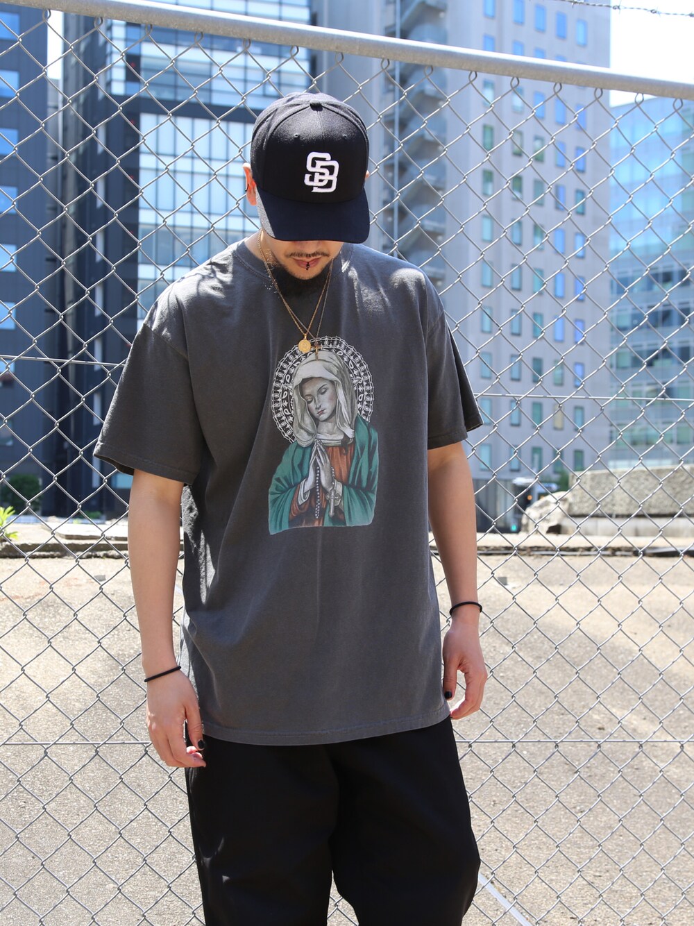 ブラック系のTシャツ/カットソー、ブラック系のキャップ、ゴールド系のネックレスを着用したメンズの春コーディネートの1枚目の写真