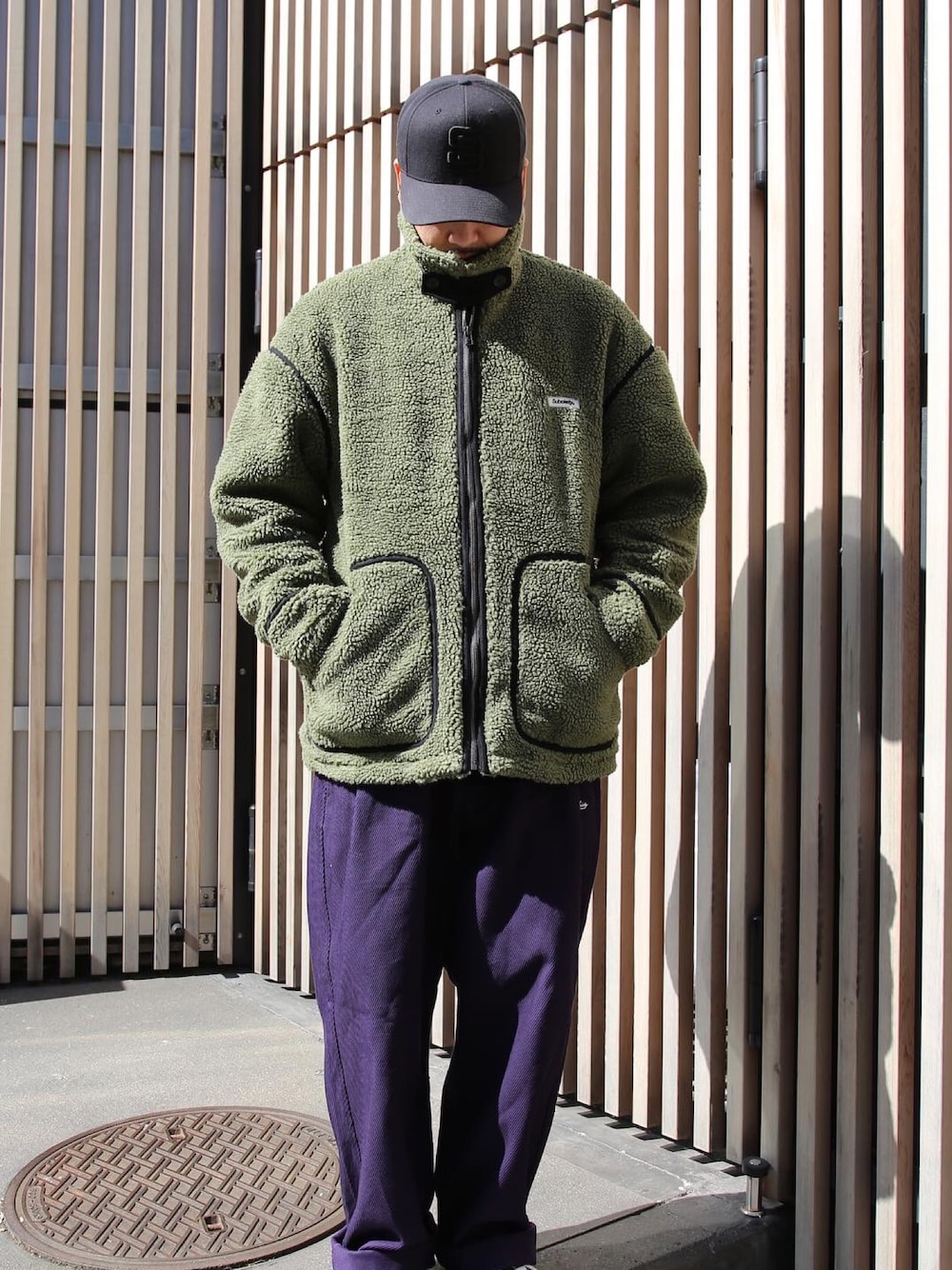 グリーン系のブルゾン、パープル系のその他パンツ、ブラック系のキャップを着用したメンズの秋コーディネートの1枚目の写真