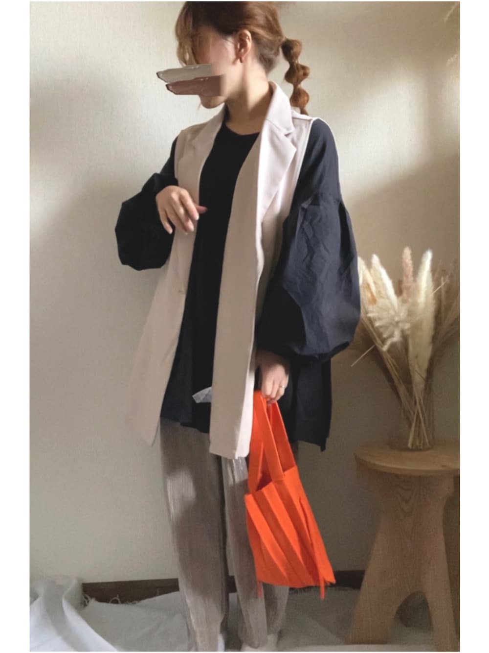 ベージュ系のベスト、オレンジ系のハンドバッグ、ブラック系のシャツ/ブラウスを着用したレディースの春コーディネートの1枚目の写真