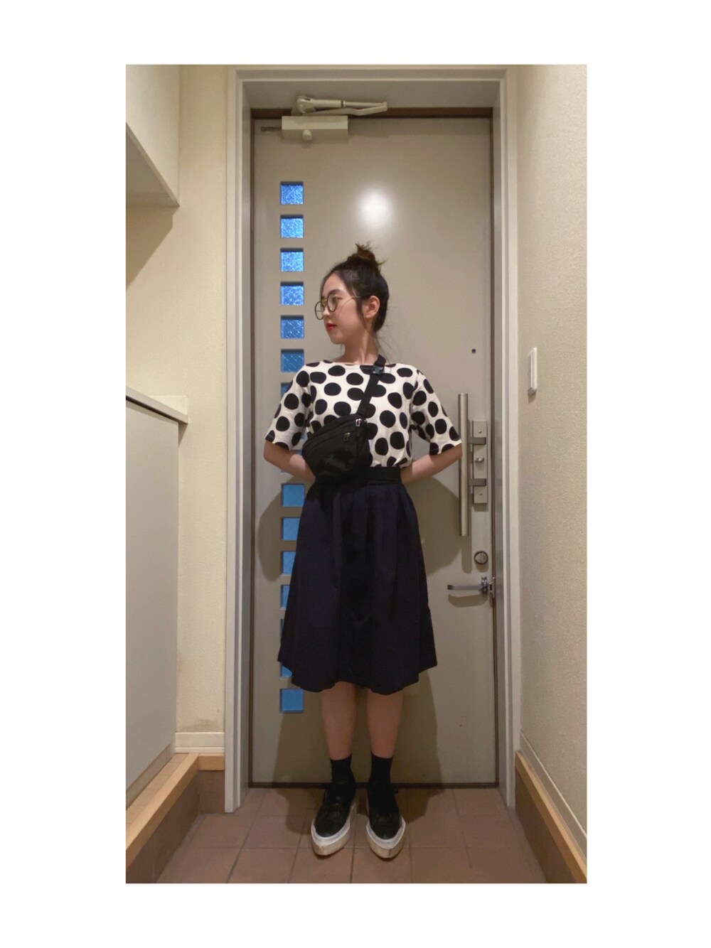 ホワイト系のTシャツ/カットソー、ブルー系のスカート、ブラック系のスニーカーを着用したレディースの秋コーディネートの1枚目の写真