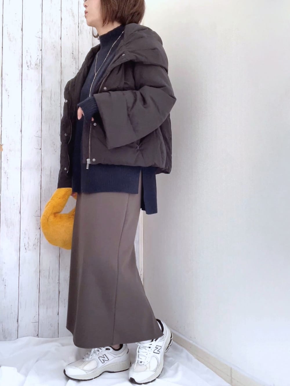 ブルー系のニット/セーター、グレー系のスカート、ホワイト系のスニーカーを着用したレディースの冬コーディネートの1枚目の写真