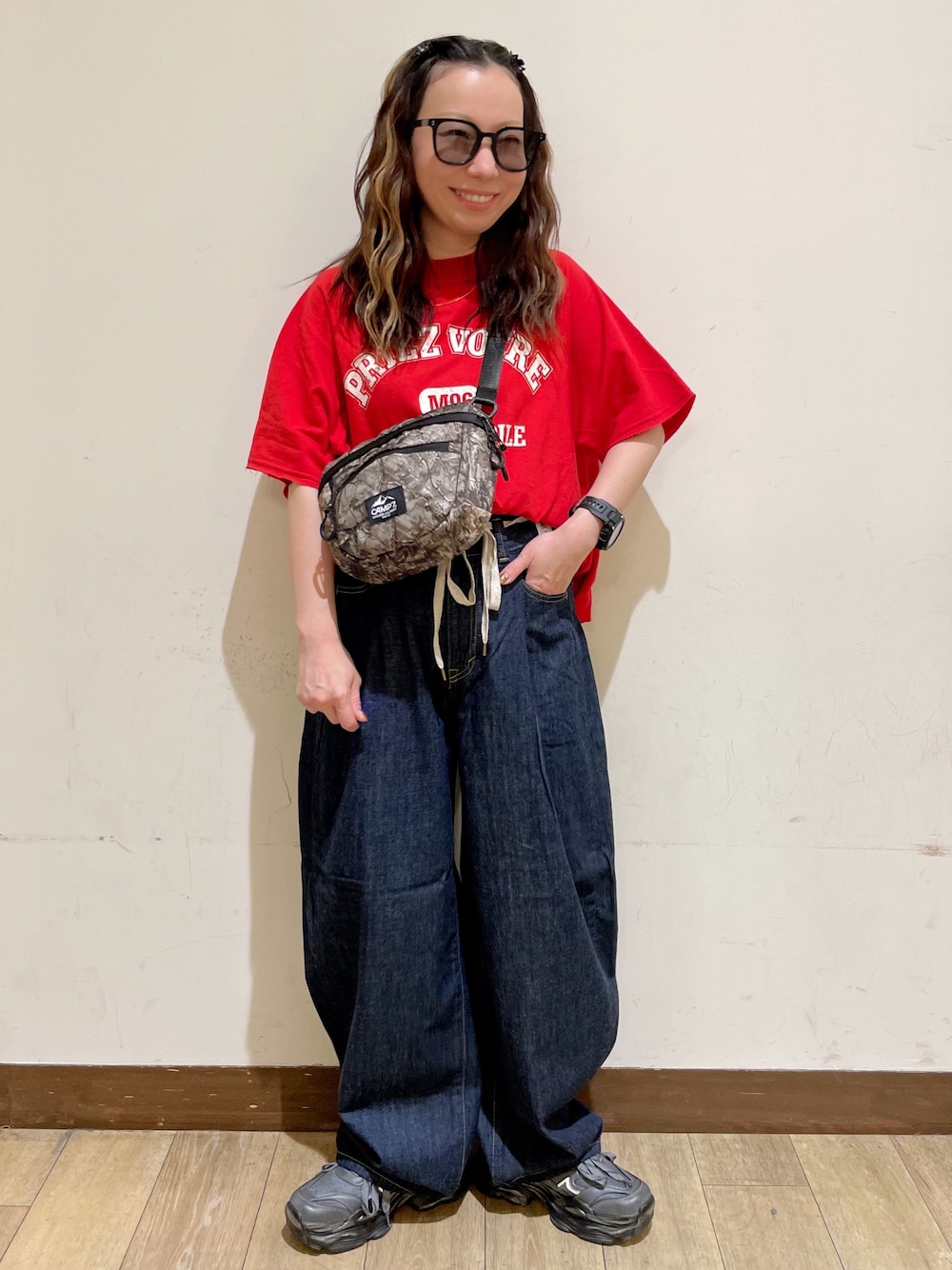 レッド系のTシャツ/カットソー、ブルー系のデニムパンツ、グリーン系のショルダーバッグを着用したレディースの夏コーディネートの1枚目の写真