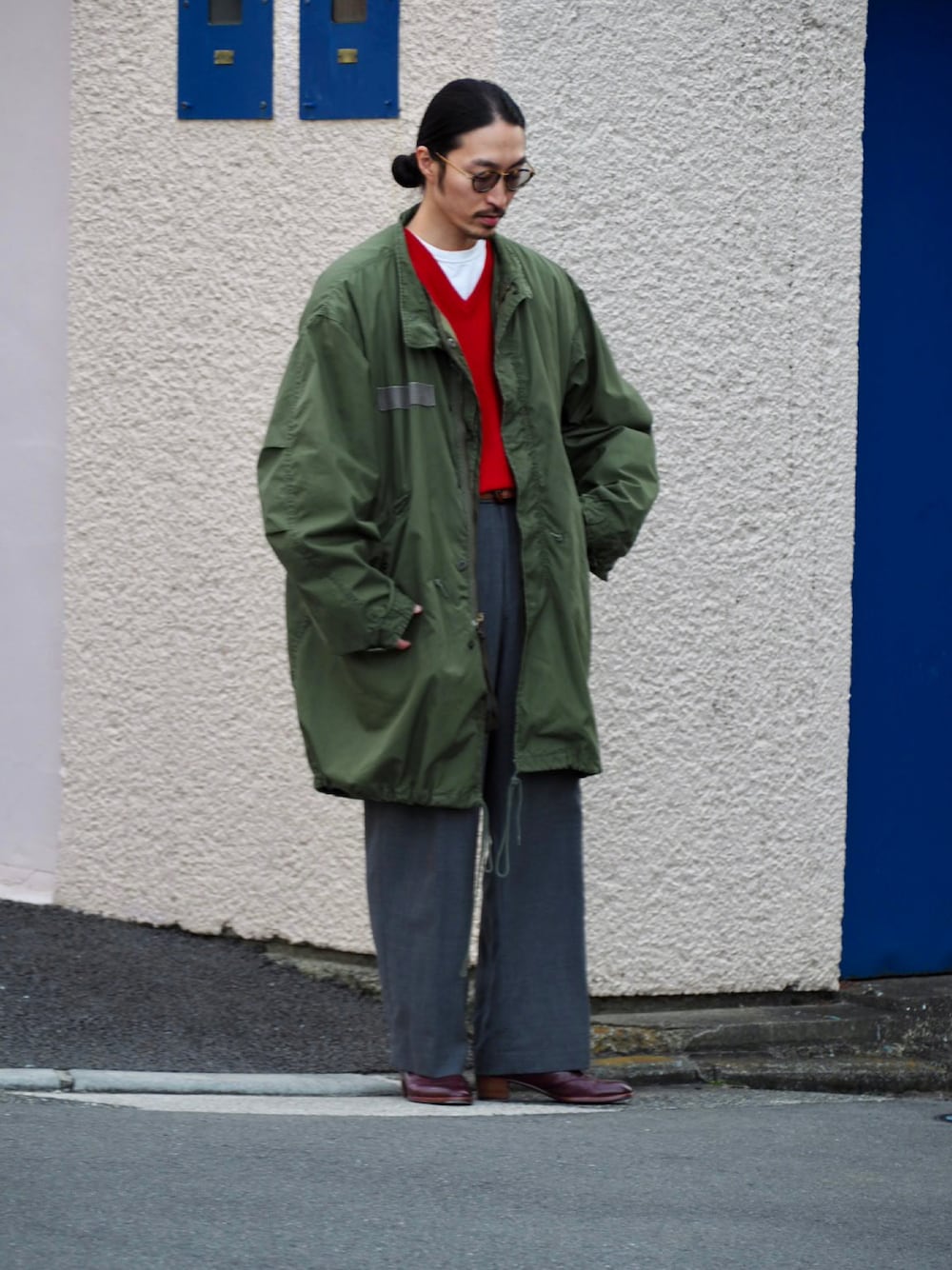 レッド系のニット/セーター、グリーン系のモッズコート、グレー系のスラックスを着用したメンズの冬コーディネートの1枚目の写真