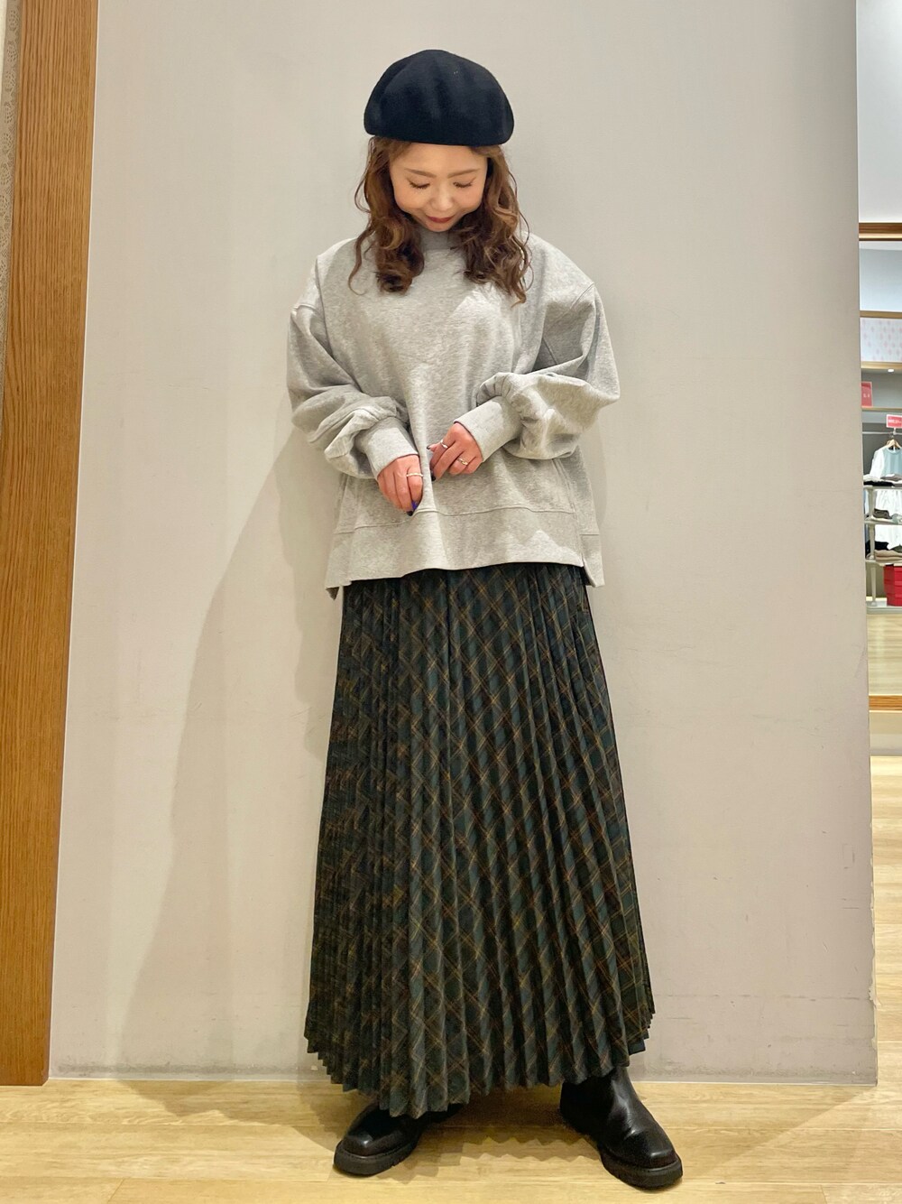 グレー系のスウェット、グリーン系のスカート、ブラック系のブーツを着用したレディースの冬コーディネートの1枚目の写真