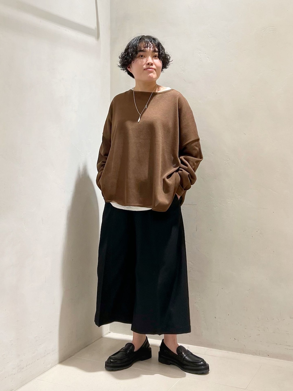 ブラック系のその他パンツ、ホワイト系のTシャツ/カットソー、ブラウン系のニット/セーターを着用したレディースの春コーディネートの1枚目の写真