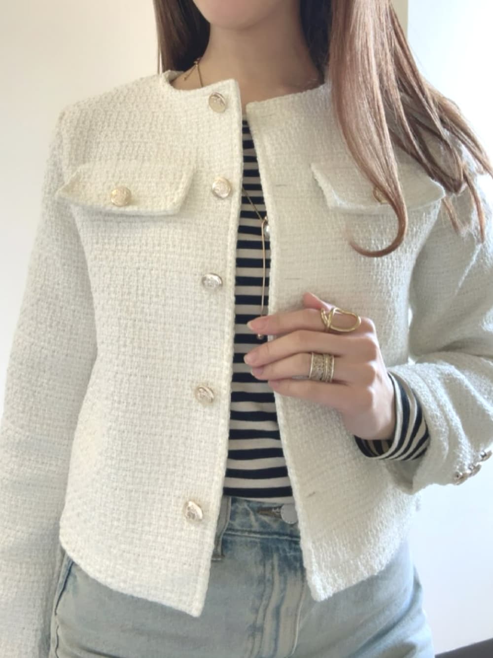 ホワイト系のノーカラージャケットを着用したレディースの冬コーディネートの1枚目の写真