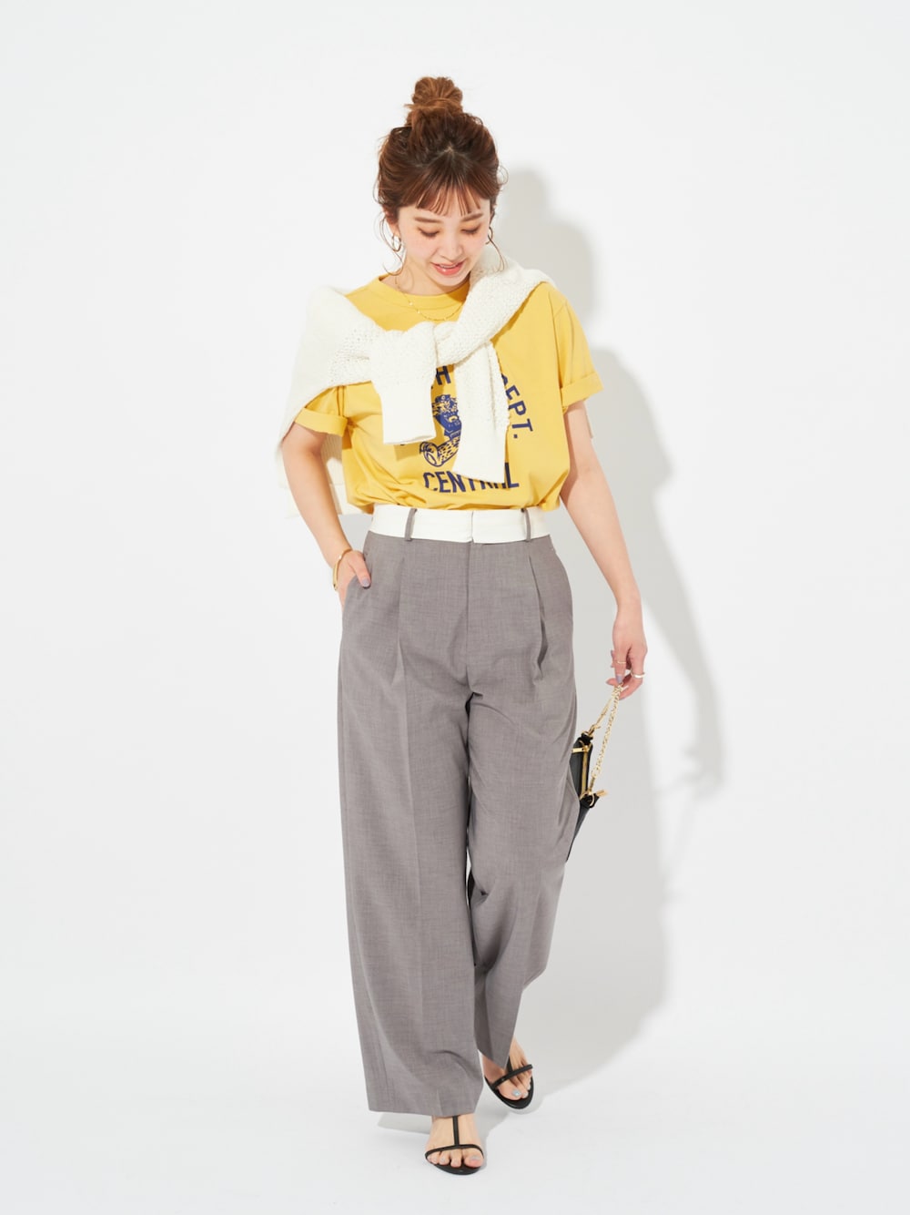 イエロー系のTシャツ/カットソー、ホワイト系のニット/セーター、グレー系のスラックスを着用したレディースの春コーディネートの1枚目の写真