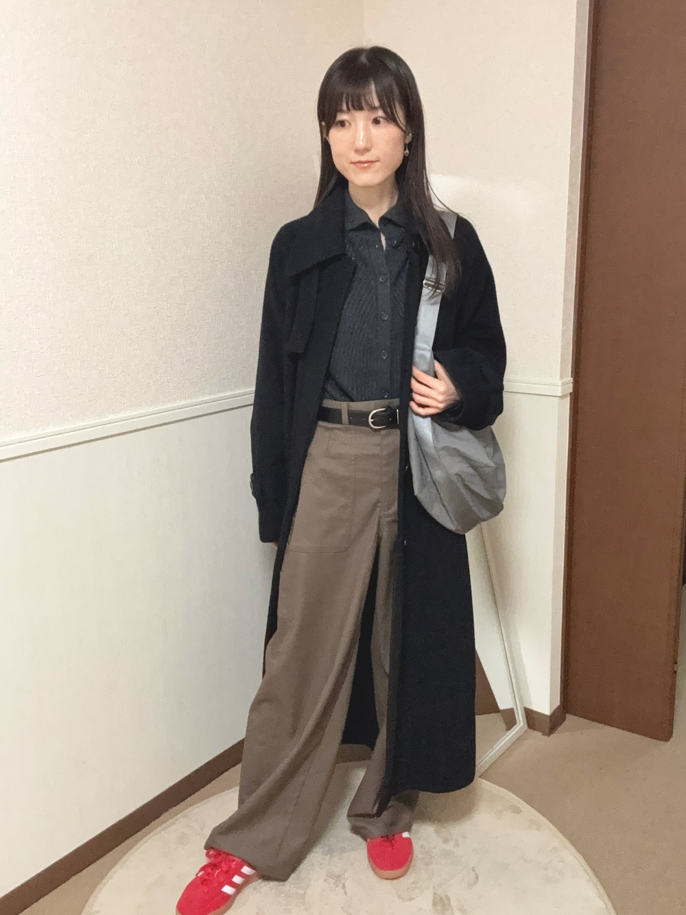 グレー系のカーディガン/ボレロ、ブラック系のステンカラーコート、ブラウン系のパンツを着用したレディースの冬コーディネートの1枚目の写真