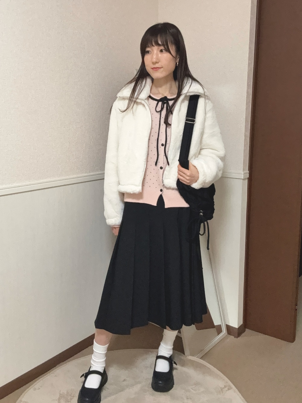 ブラック系のスニーカー、ブラック系のスカート、ホワイト系のブルゾンを着用したレディースの冬コーディネートの1枚目の写真