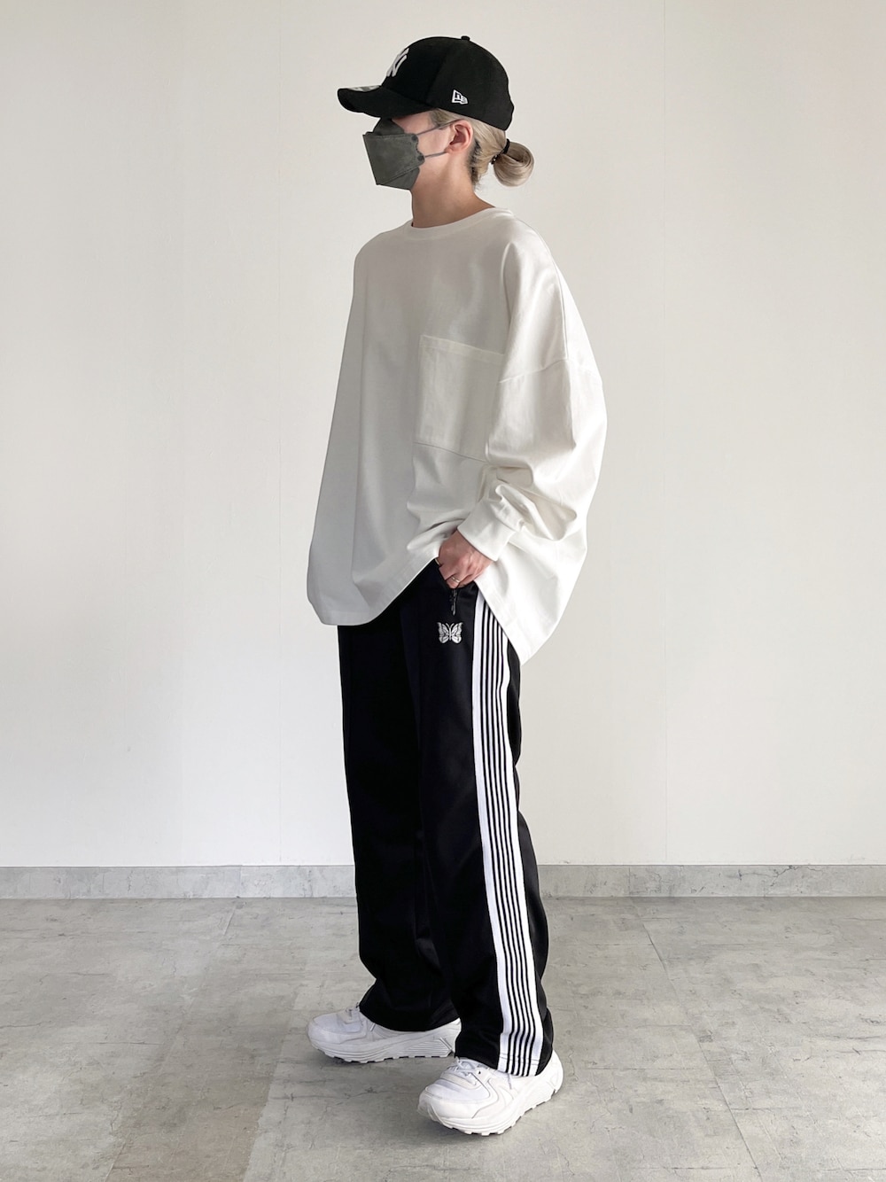 ホワイト系のTシャツ/カットソー、ブラック系のパンツ、ホワイト系のスニーカーを着用したレディースの春コーディネートの1枚目の写真