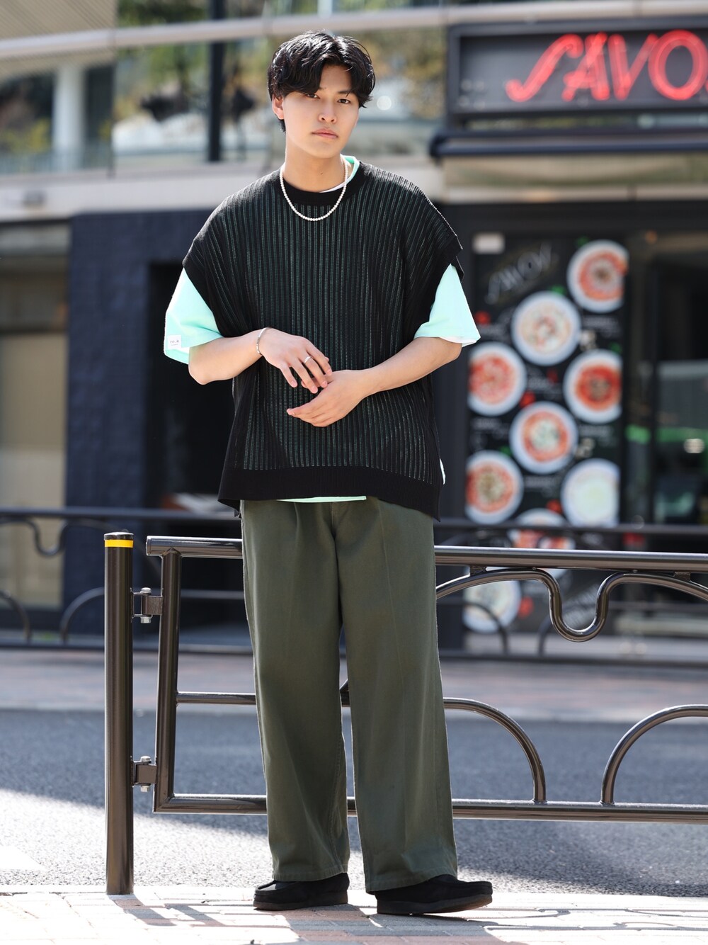 ブラック系のベスト、グリーン系のTシャツ/カットソー、グリーン系のデニムパンツを着用したメンズの春コーディネートの1枚目の写真
