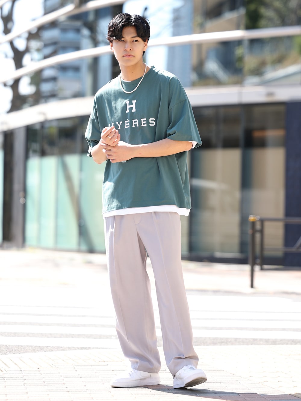 グリーン系のTシャツ/カットソー、グレー系のスラックス、ホワイト系のスニーカーを着用したメンズの春コーディネートの1枚目の写真