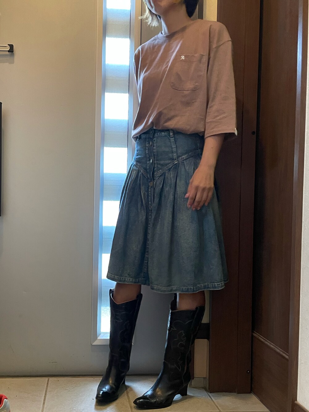 ブラウン系のTシャツ/カットソー、ブルー系のデニムスカート、ブラック系のブーツを着用したレディースの秋コーディネートの1枚目の写真