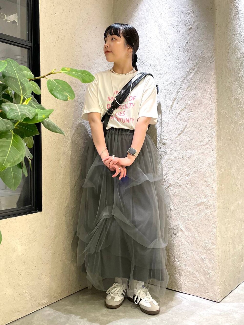 グレー系のスカート、ホワイト系のTシャツ/カットソー、ブラック系のショルダーバッグを着用したレディースの夏コーディネートの1枚目の写真