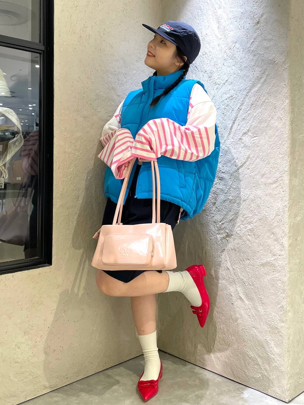 レッド系のパンプス、ブルー系のスウェットパンツ、ブルー系のダウンベストを着用したレディースの秋コーディネートの1枚目の写真