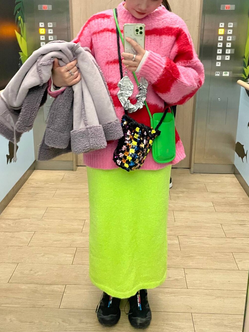 グリーン系のスカート、シルバー系のネックレスを着用したレディースの冬コーディネートの1枚目の写真