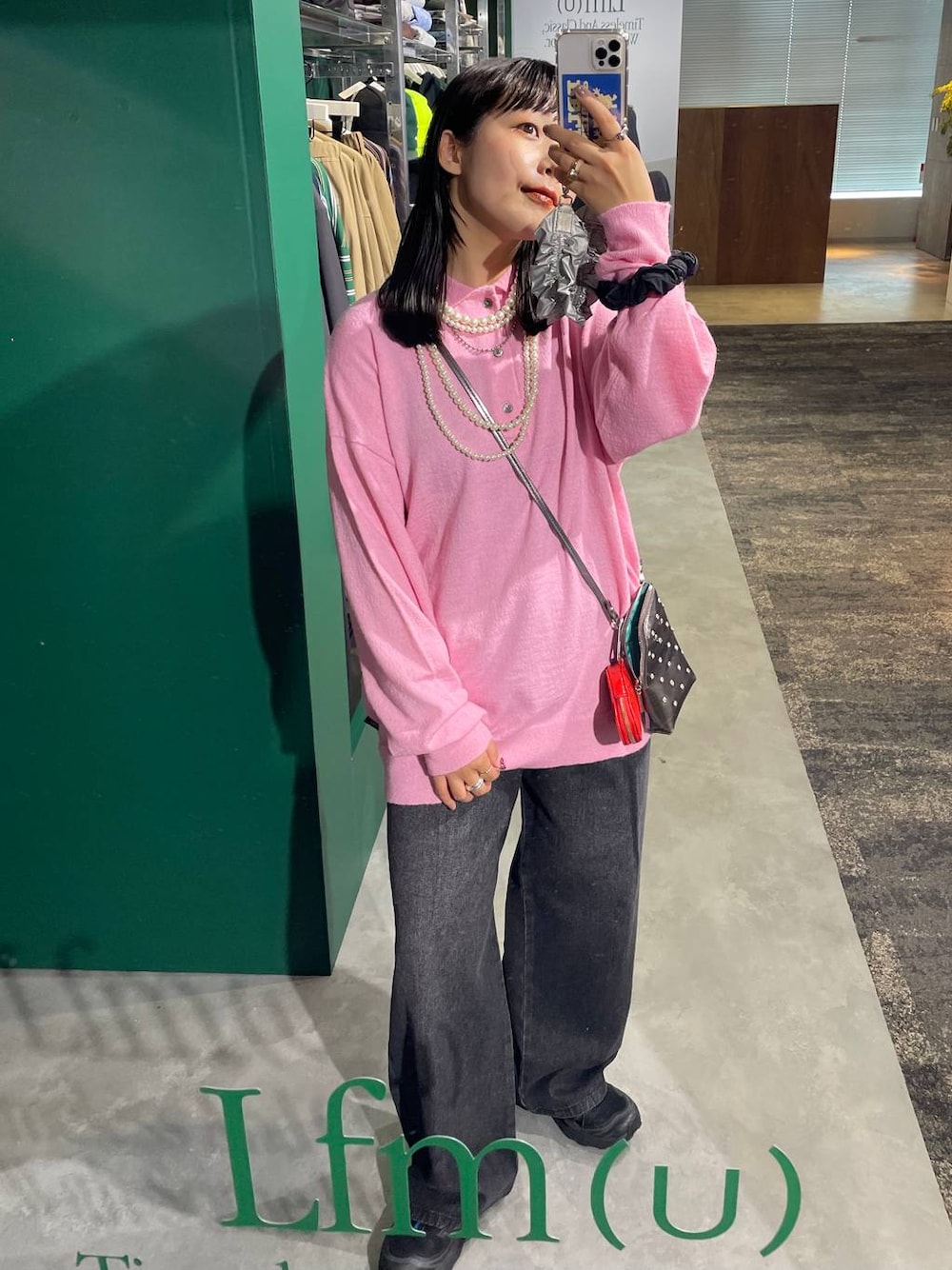 ブラック系のデニムパンツ、ピンク系のニット/セーター、ベージュ系のネックレスを着用したレディースの夏コーディネートの1枚目の写真