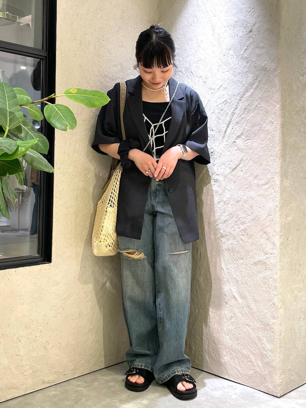 ベージュ系のショルダーバッグ、ブラック系のTシャツ/カットソー、ブルー系のデニムパンツを着用したレディースの夏コーディネートの1枚目の写真