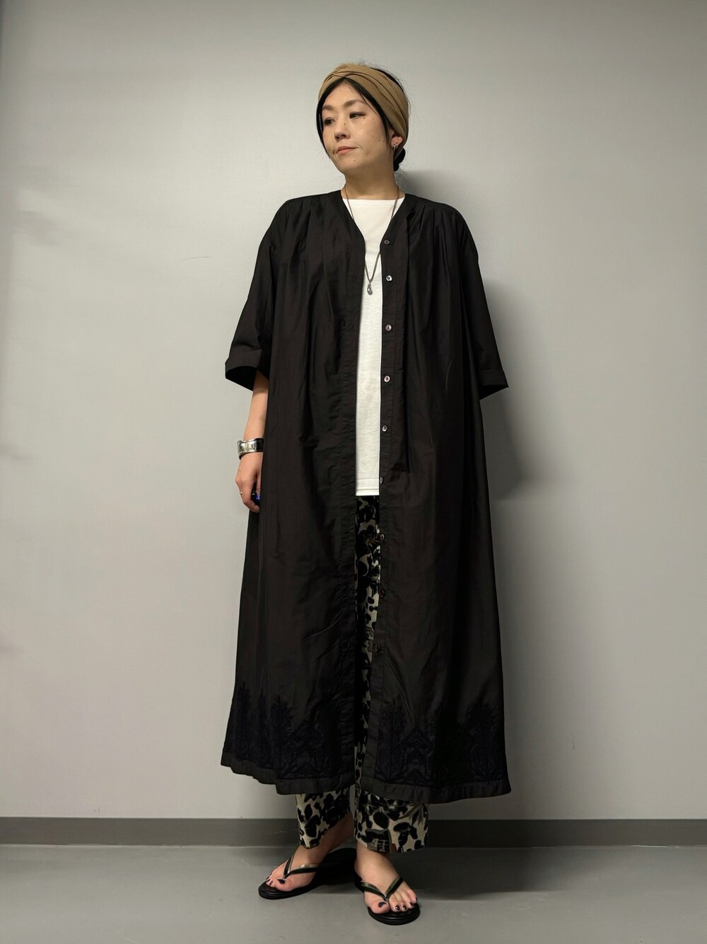 ブラック系のワンピース、ブラック系のサンダル、ホワイト系のTシャツ/カットソーを着用したレディースの夏コーディネートの1枚目の写真