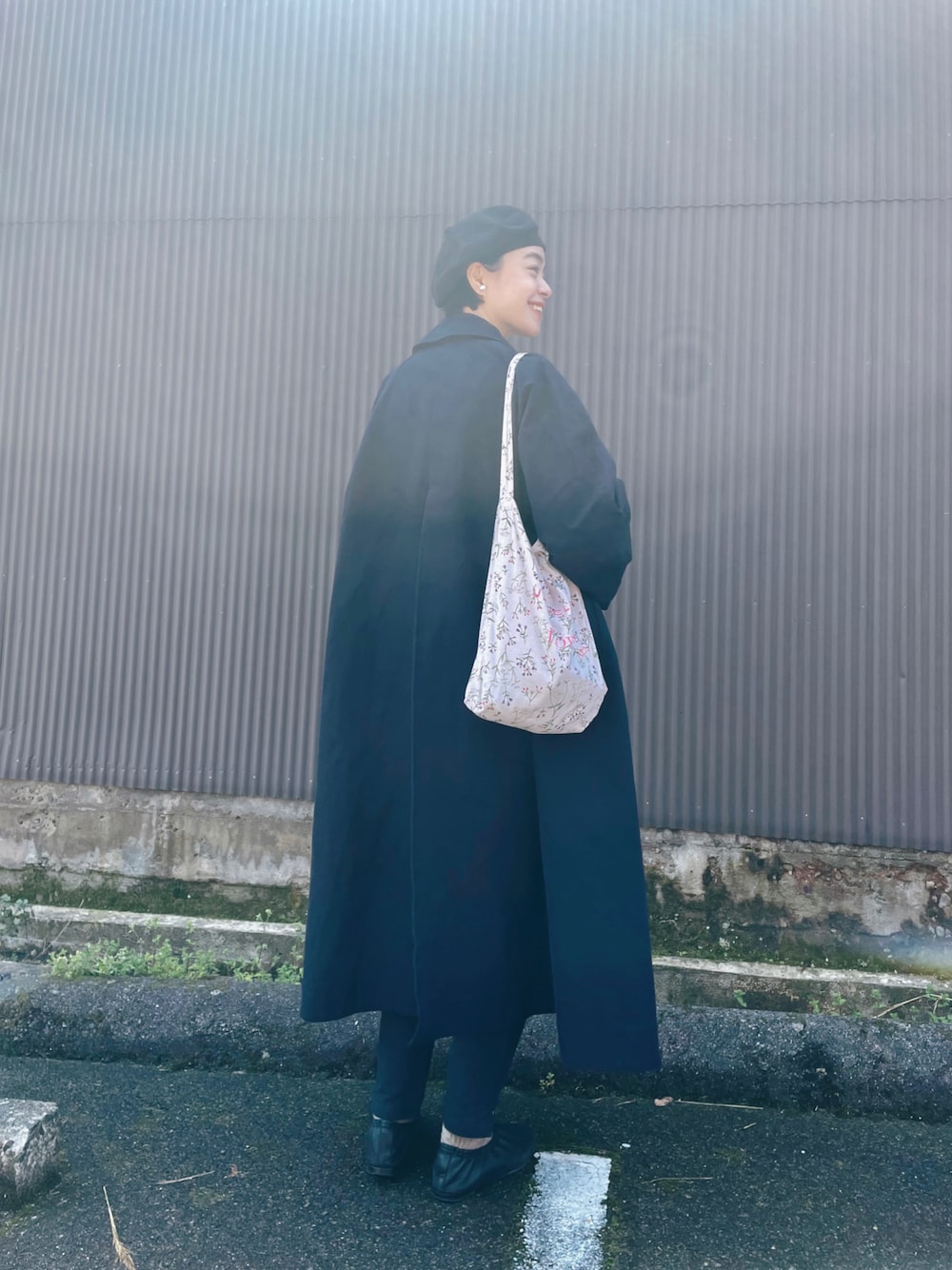 ピンク系のトートバッグ、ブルー系のステンカラーコート、ブラック系のパンツを着用したレディースの春コーディネートの1枚目の写真