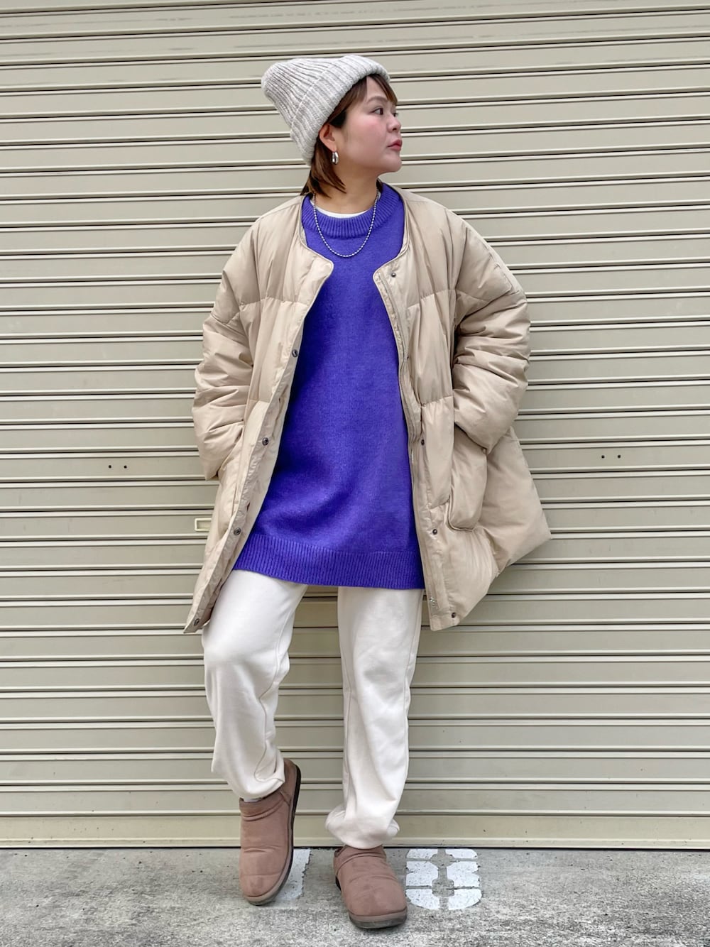 ベージュ系のダウンジャケット/コート、パープル系のニット/セーター、ホワイト系のニットキャップ/ビーニーを着用したレディースの冬コーディネートの1枚目の写真