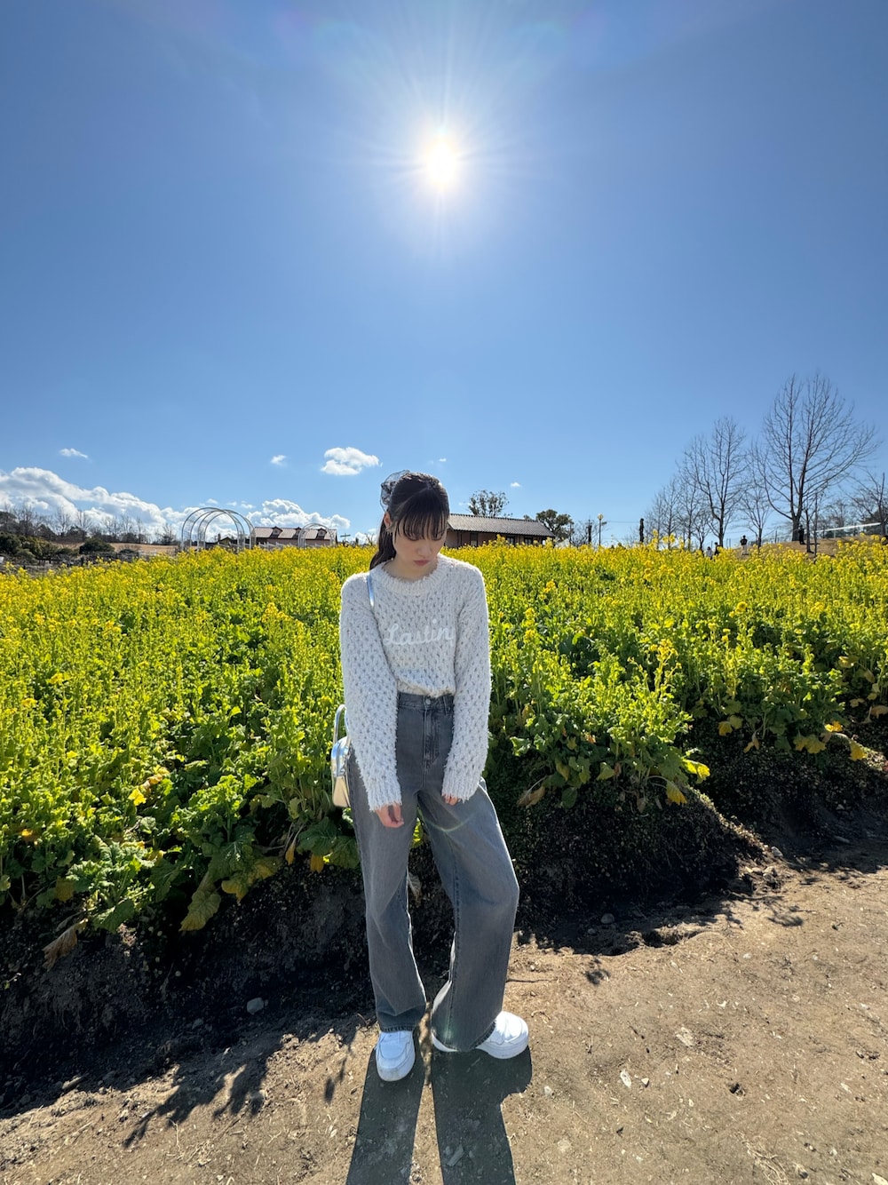 グレー系のデニムパンツ、ホワイト系のスニーカー、ベージュ系のニット/セーターを着用したレディースの冬コーディネートの1枚目の写真