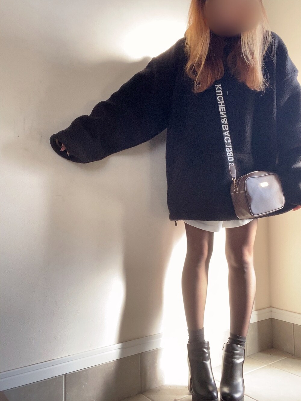 ブラック系のパーカー、ブラウン系のバッグ、ホワイト系のTシャツ/カットソーを着用したレディースの冬コーディネートの1枚目の写真