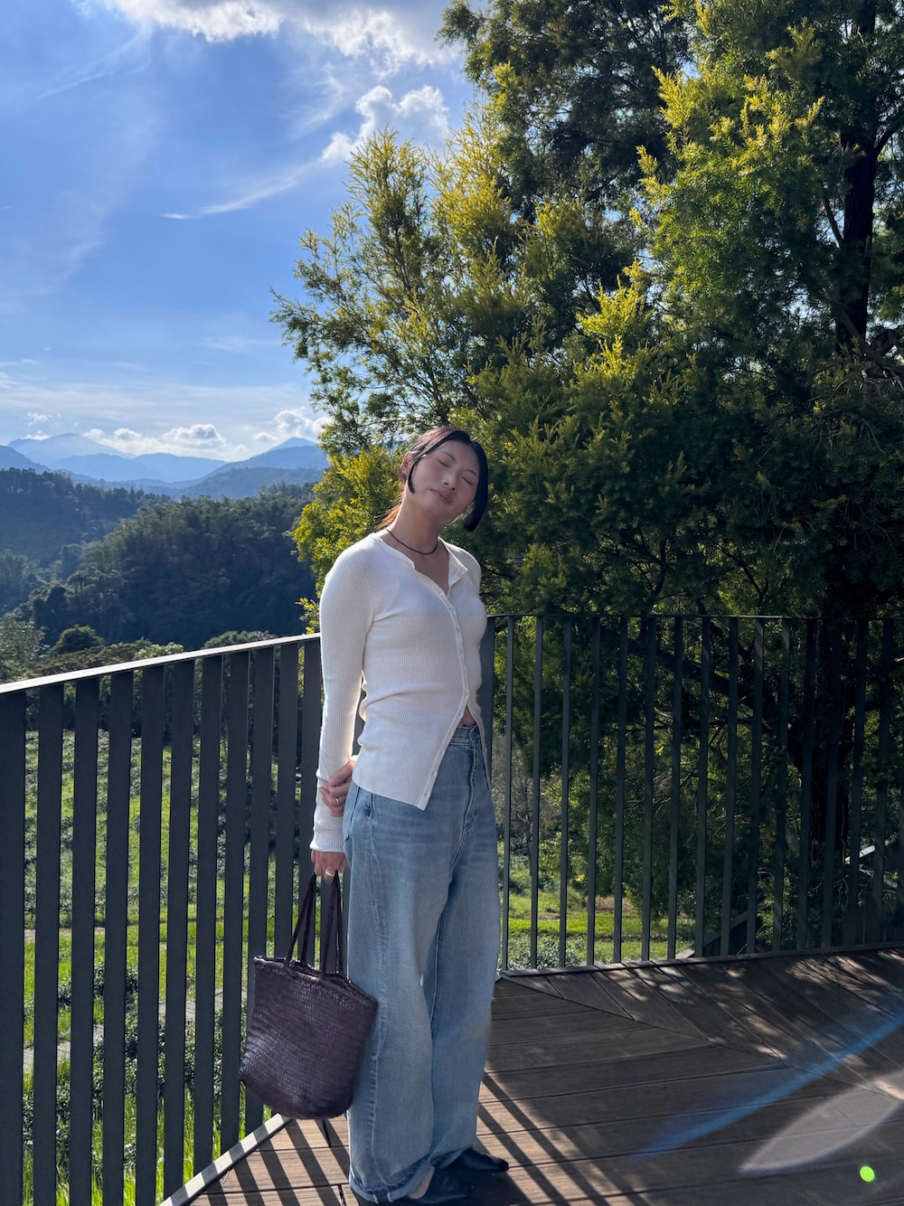 ホワイト系のニット/セーター、ブルー系のデニムパンツ、ブラウン系のトートバッグを着用したレディースの秋コーディネートの1枚目の写真