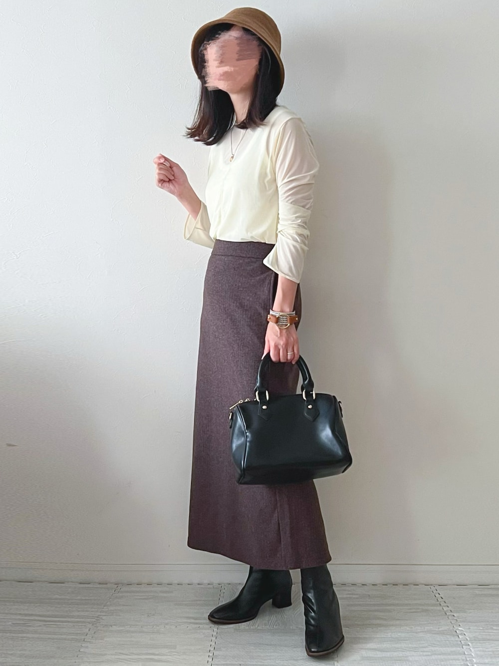 ブラック系のボストンバッグ、ブラック系のブーツ、ブラウン系のスカートを着用したレディースの秋コーディネートの1枚目の写真