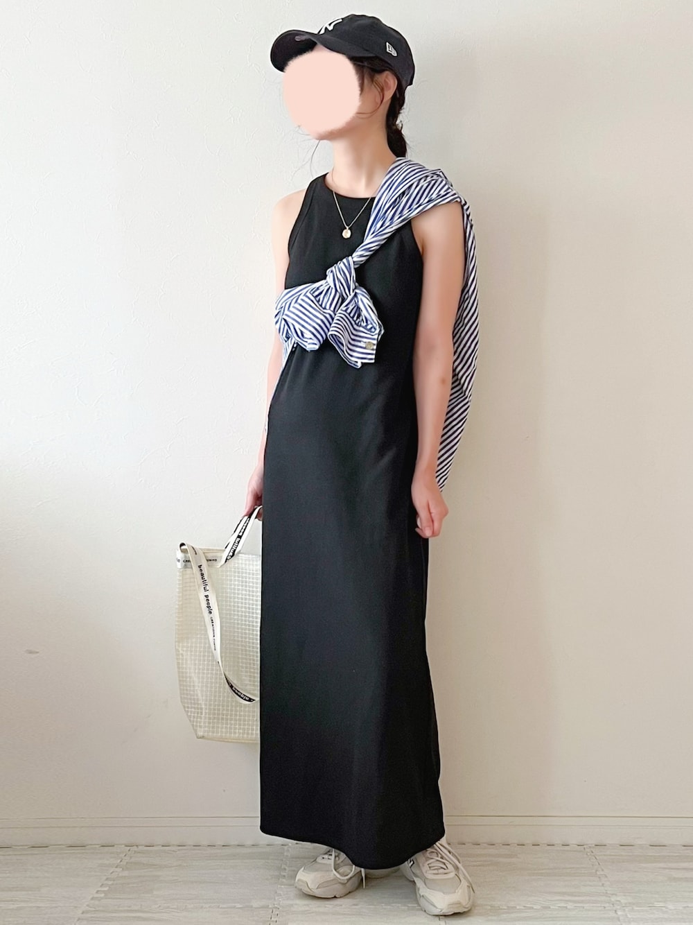 ベージュ系のスニーカー、ホワイト系のショルダーバッグ、ブラック系のワンピースを着用したレディースの夏コーディネートの1枚目の写真