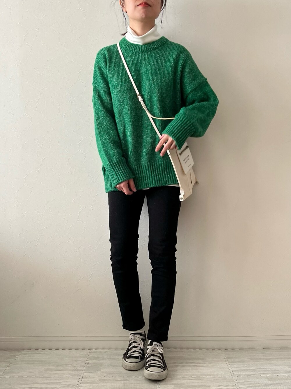 グリーン系のニット/セーター、ホワイト系のTシャツ/カットソー、ホワイト系のショルダーバッグを着用したレディースの冬コーディネートの1枚目の写真