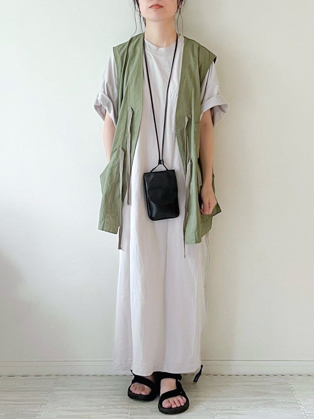 グリーン系のベスト、ブラック系のショルダーバッグ、グレー系のワンピースを着用したレディースの夏コーディネートの1枚目の写真