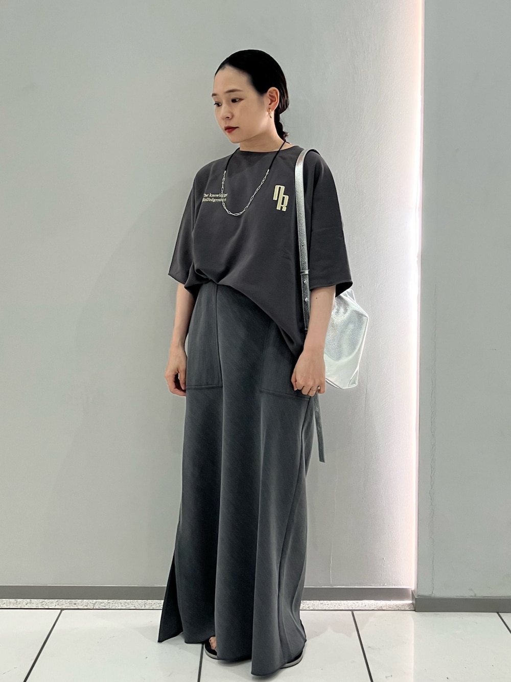 グレー系のTシャツ/カットソー、グレー系のスカート、シルバー系のネックレスを着用したレディースの秋コーディネートの1枚目の写真