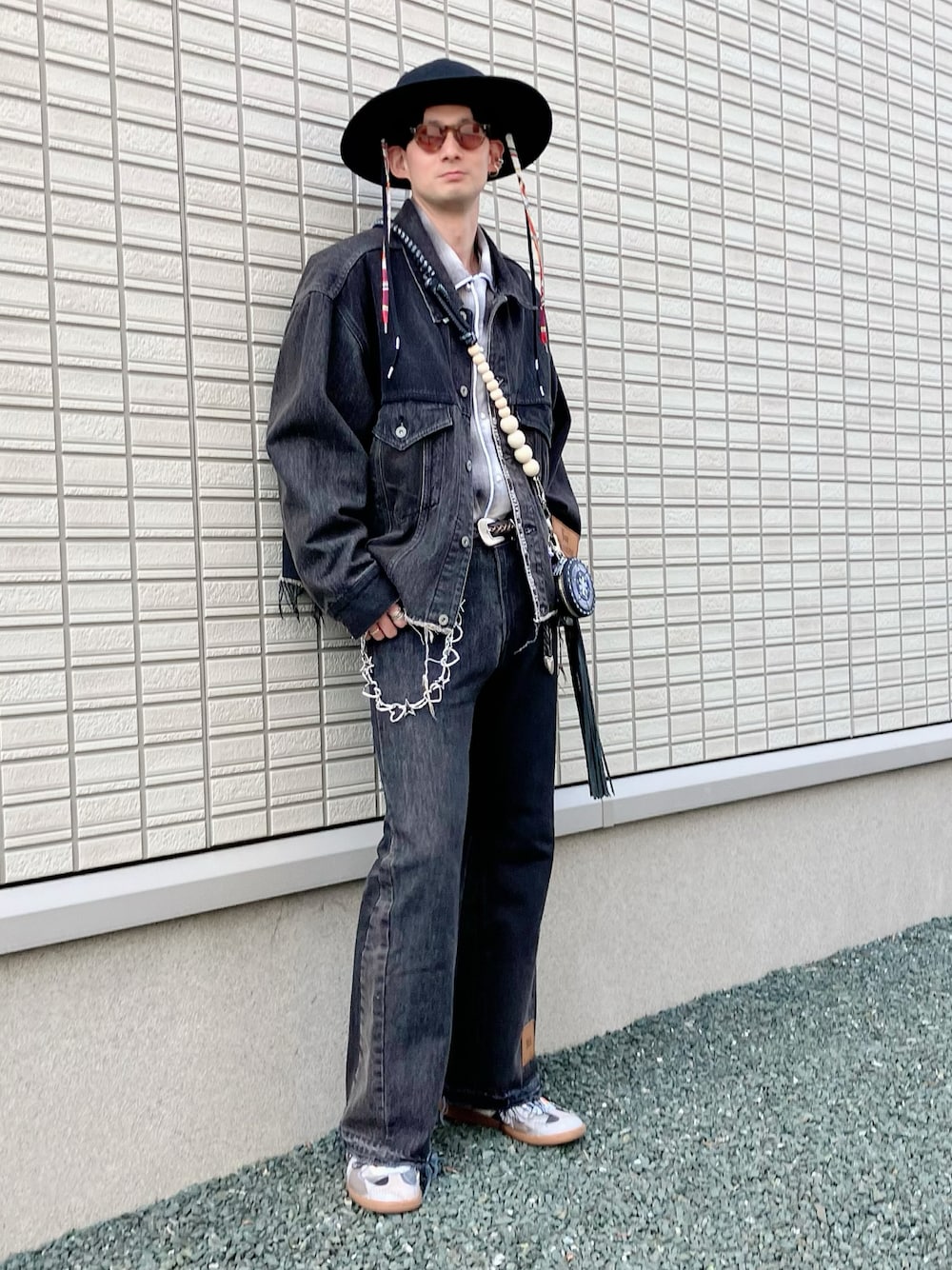 ブラック系のデニムジャケット、ブラック系のデニムパンツ、ホワイト系のスニーカーを着用したメンズの春コーディネートの1枚目の写真