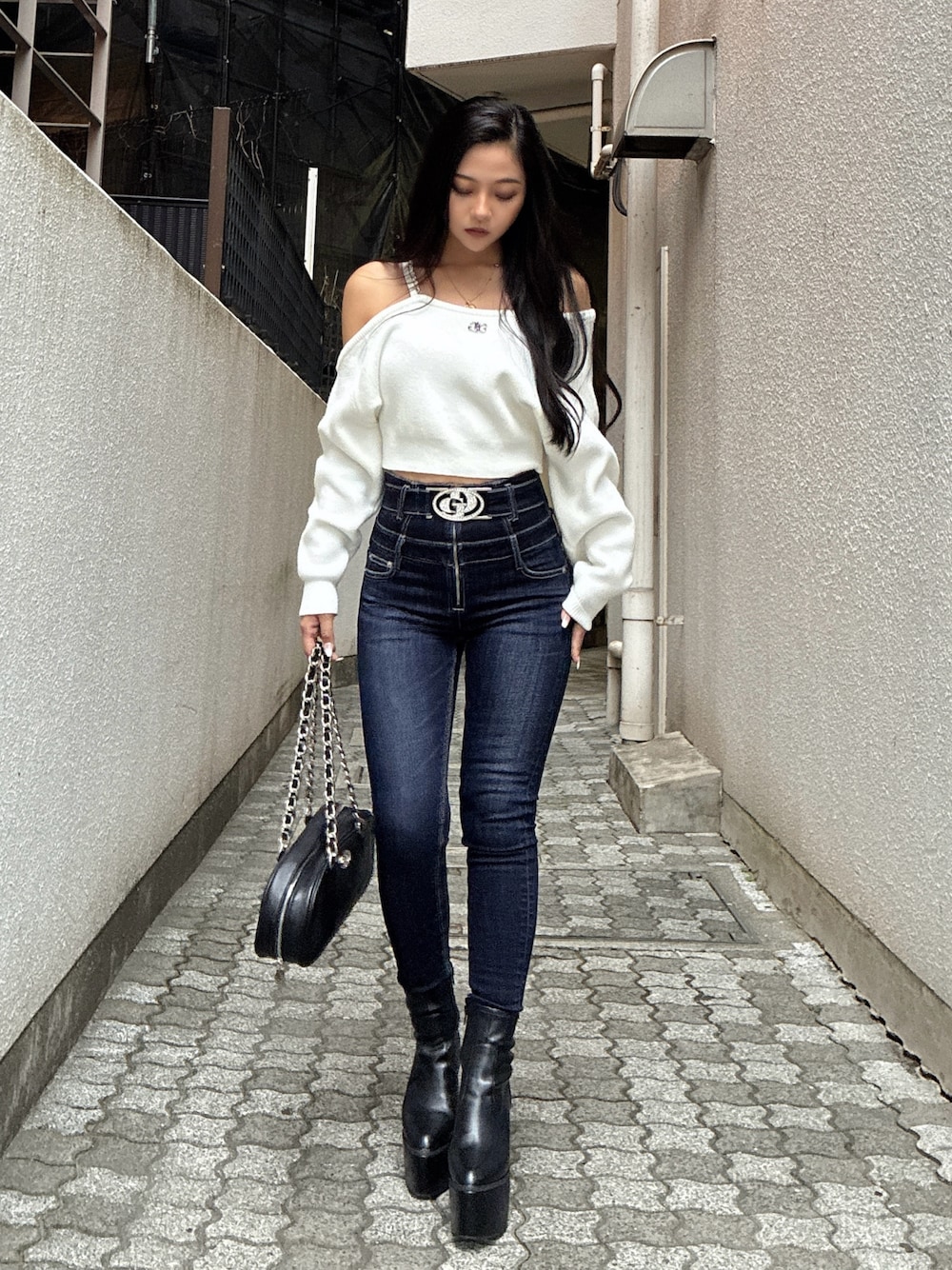 ホワイト系のニット/セーター、ブルー系のデニムパンツ、ブラック系のブーツを着用したレディースの秋コーディネートの1枚目の写真