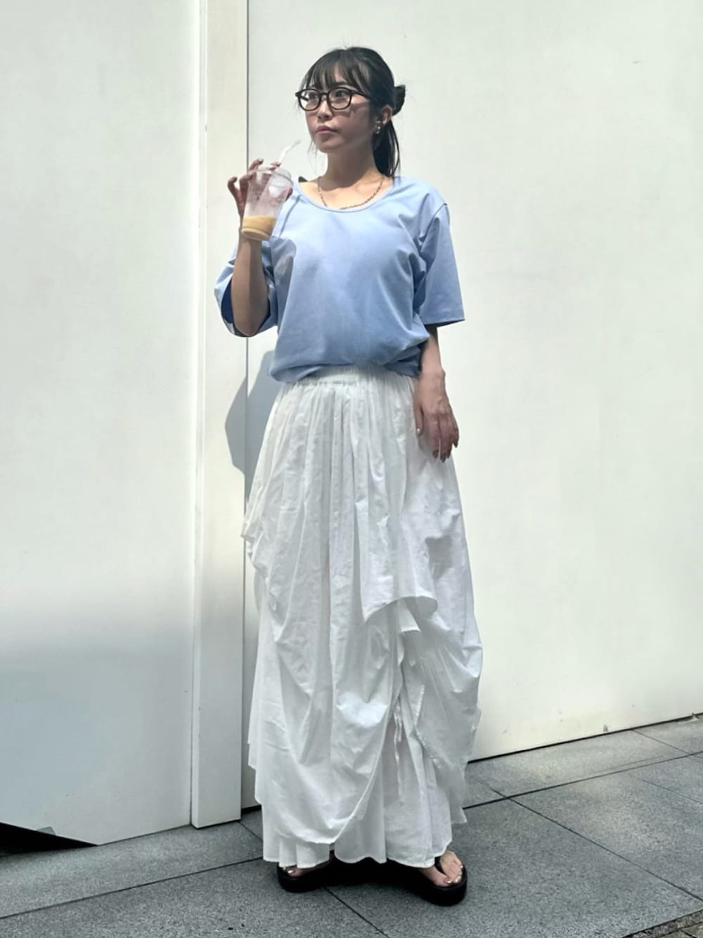 ホワイト系のスカート、ブルー系のTシャツ/カットソー、ブラック系のサンダルを着用したレディースの夏コーディネートの1枚目の写真