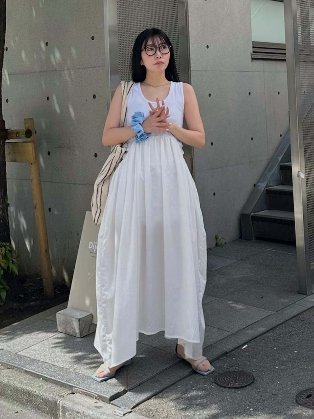 ホワイト系のワンピース、ベージュ系のトートバッグ、ブルー系のサンダルを着用したレディースの春コーディネートの1枚目の写真