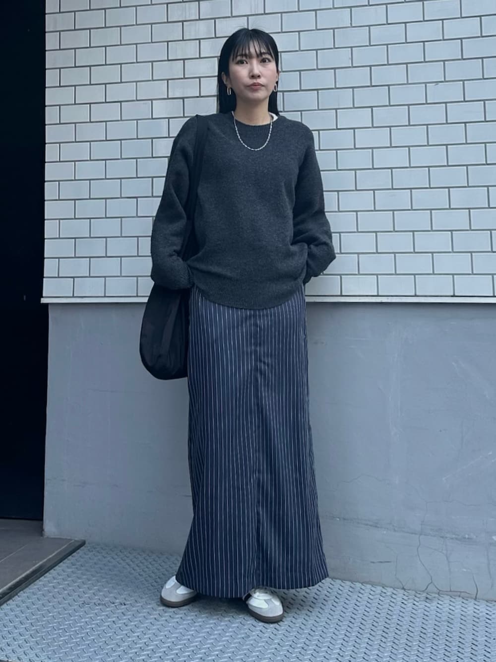 ホワイト系のスニーカー、ブルー系のスカート、グレー系のニット/セーターを着用したレディースの冬コーディネートの1枚目の写真