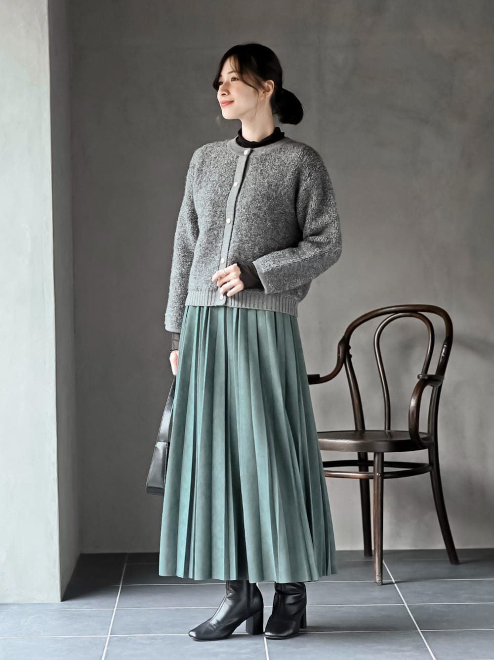 グリーン系のスカート、グレー系のカーディガン/ボレロ、ブラック系のTシャツ/カットソーを着用したレディースの秋コーディネートの1枚目の写真