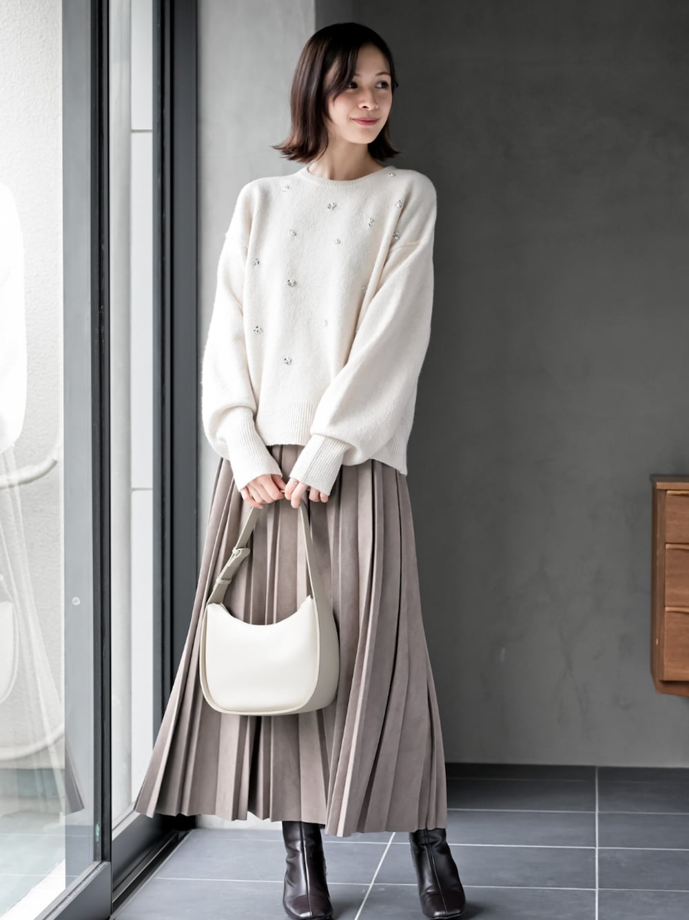 ブラウン系のスカート、ホワイト系のニット/セーターを着用したレディースの秋コーディネートの1枚目の写真