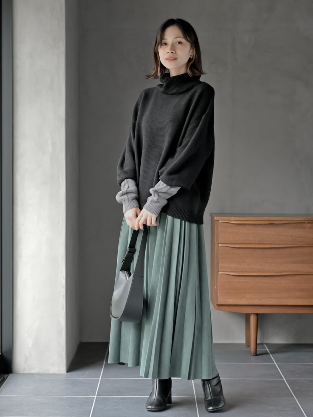 グリーン系のスカート、ブラック系のニット/セーターを着用したレディースの秋コーディネートの1枚目の写真