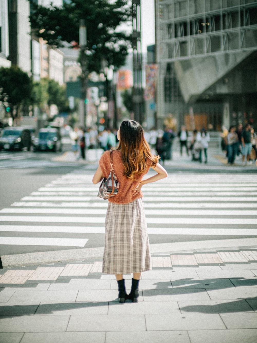 オレンジ系のニット/セーター、ブラウン系のショルダーバッグ、ホワイト系のスカートを着用したレディースの秋コーディネートの1枚目の写真