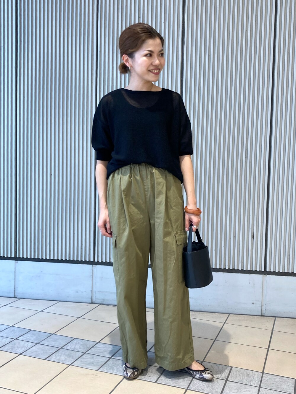 ブラック系のニット/セーター、グリーン系のその他パンツ、ブラック系のショルダーバッグを着用したレディースの夏コーディネートの1枚目の写真