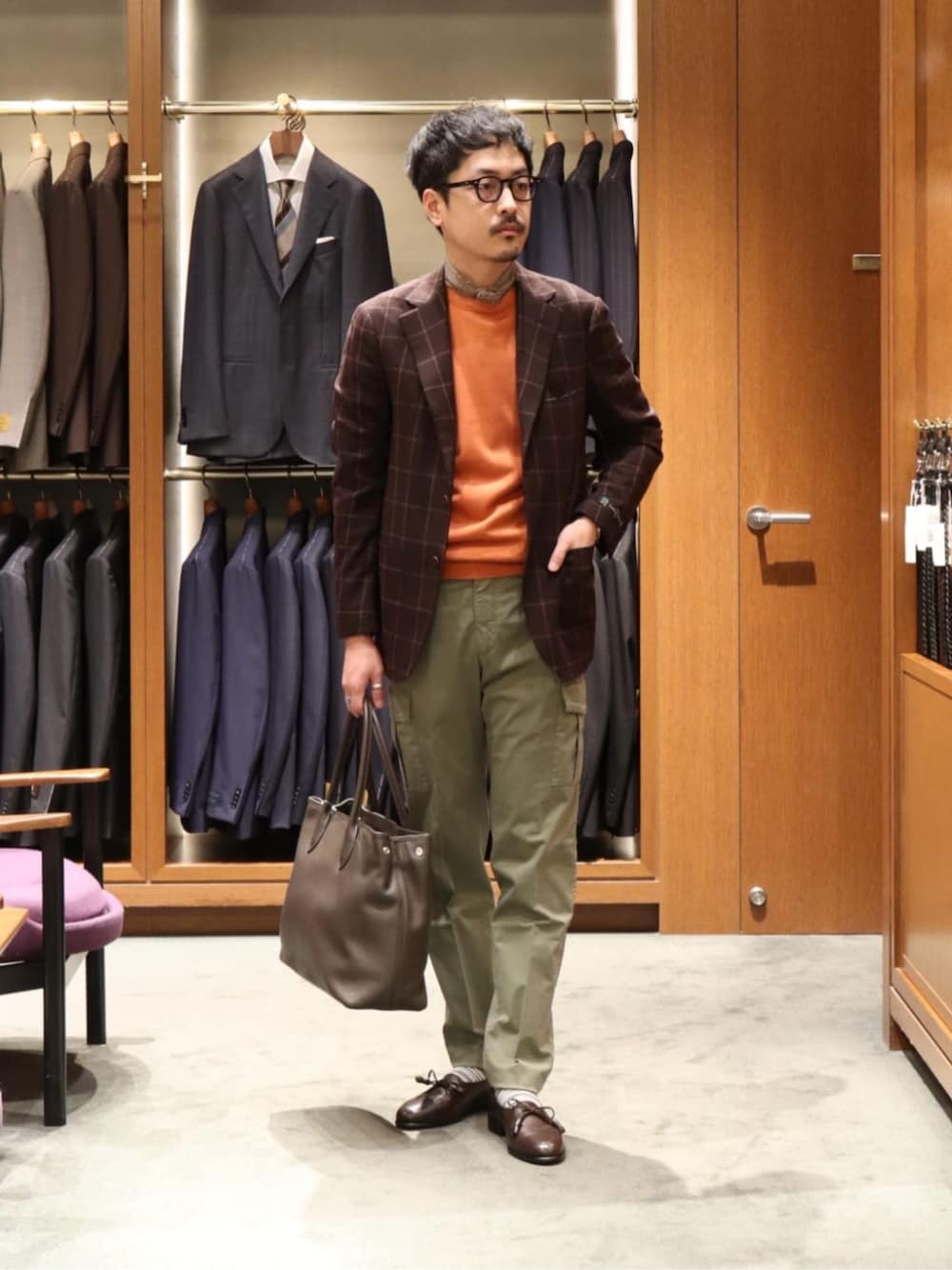 ブラウン系のドレスシューズ、ブラウン系のテーラードジャケット、オレンジ系のニット/セーターを着用したメンズの春コーディネートの1枚目の写真