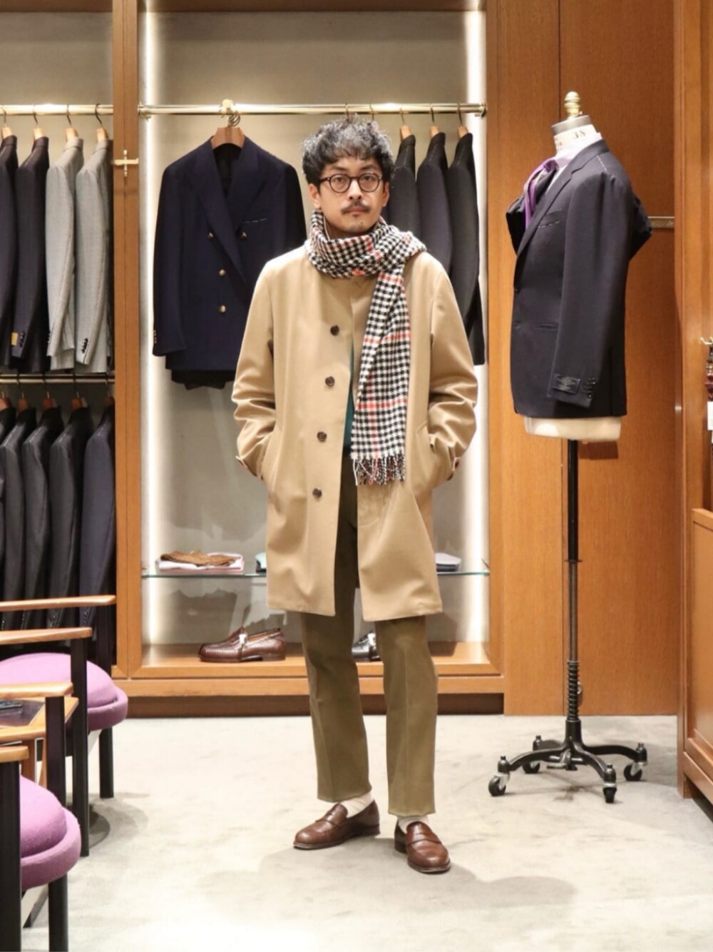 グリーン系のチノパンツ、ベージュ系のステンカラーコート、グリーン系のニット/セーターを着用したメンズの冬コーディネートの1枚目の写真