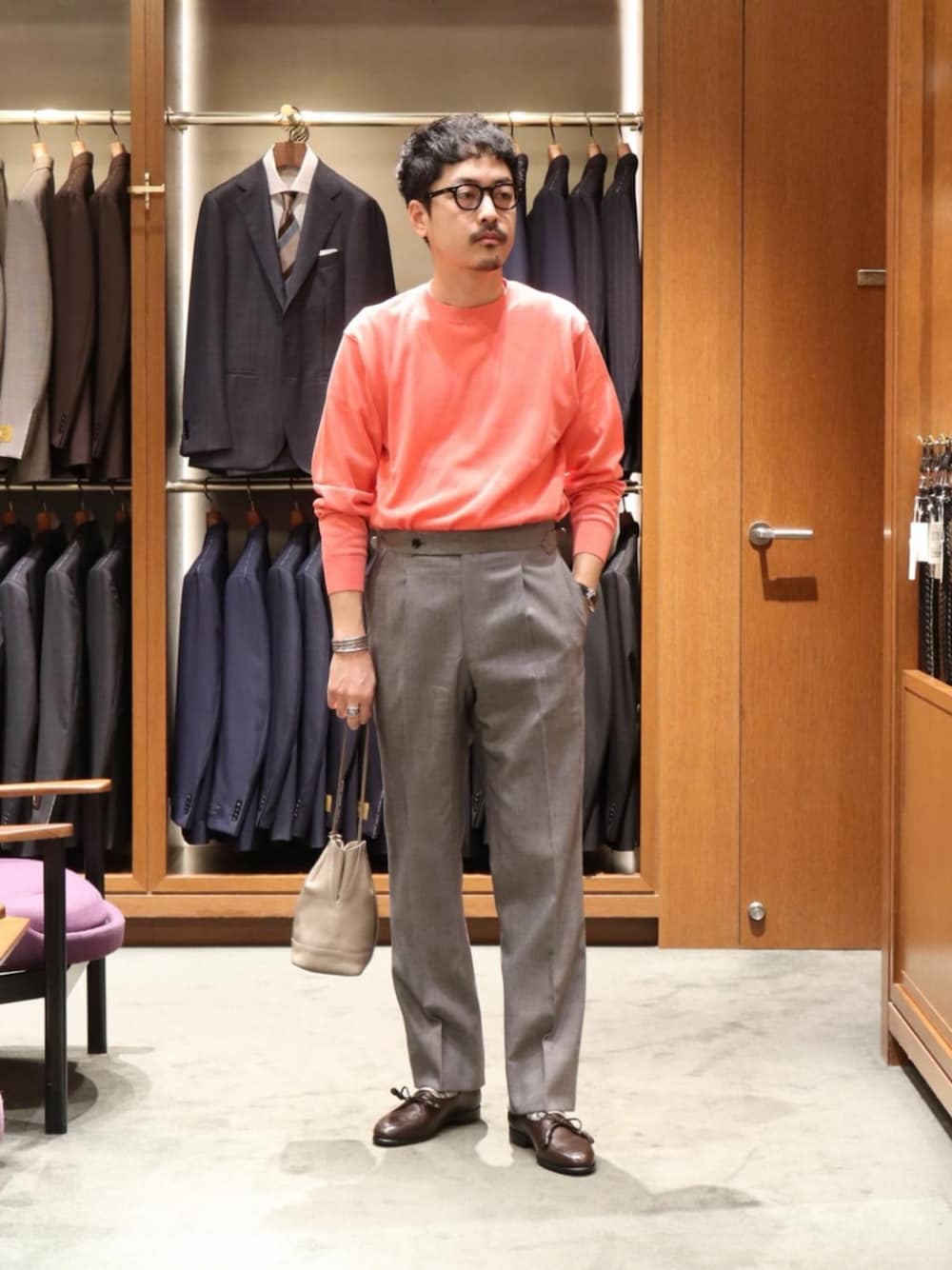 ブラウン系のドレスシューズ、グレー系のスラックス、ベージュ系のショルダーバッグを着用したメンズの春コーディネートの1枚目の写真