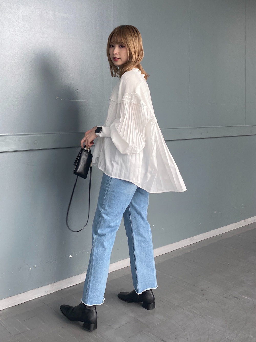 ホワイト系のニット/セーター、ブルー系のデニムパンツ、ブラック系のショルダーバッグを着用したレディースの冬コーディネートの1枚目の写真